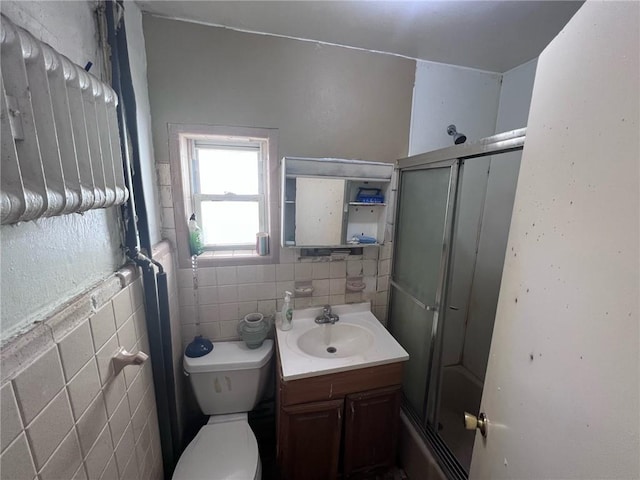 bathroom featuring vanity, toilet, and tile walls