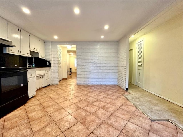 kitchen with oven, white cabinets, and brick wall