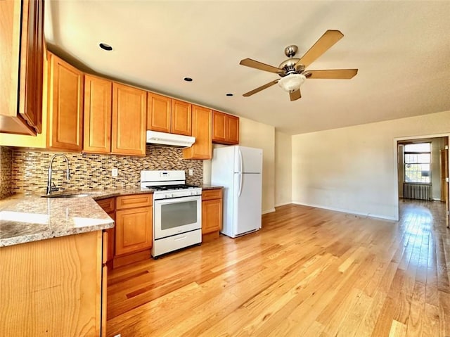 kitchen with radiator, ceiling fan, sink, white appliances, and light wood-type flooring