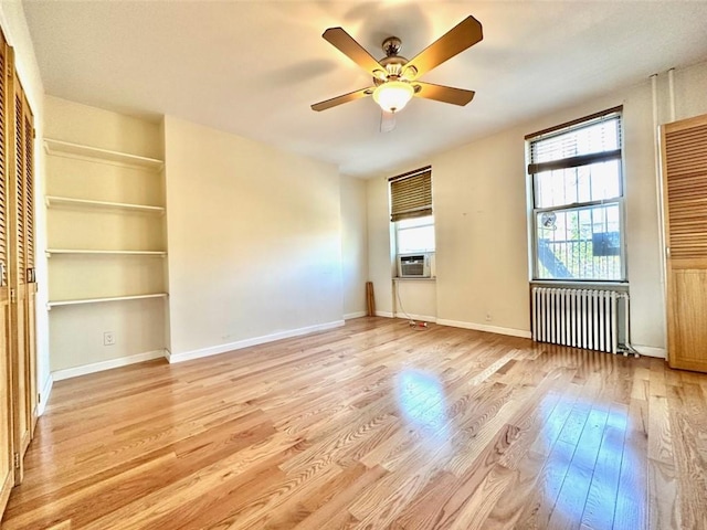 unfurnished living room featuring light wood-type flooring, radiator, cooling unit, and ceiling fan