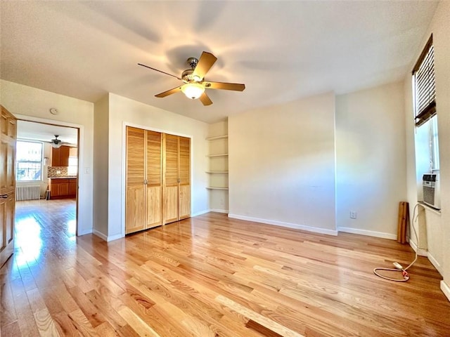 unfurnished bedroom with a closet, ceiling fan, radiator heating unit, and light hardwood / wood-style floors