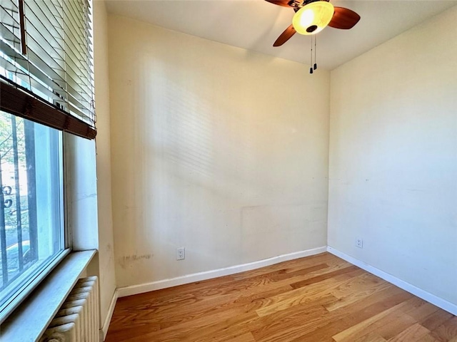 empty room with ceiling fan, light hardwood / wood-style floors, and radiator