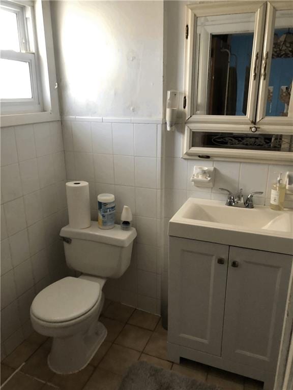 bathroom with tile patterned flooring, toilet, vanity, and tile walls