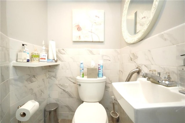 bathroom featuring sink, tile walls, and toilet