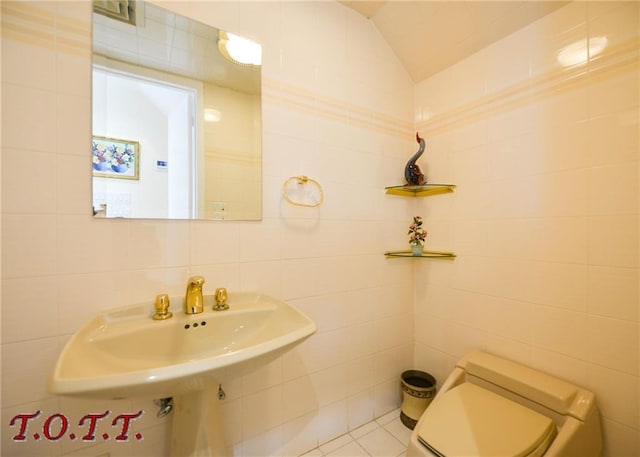 bathroom featuring lofted ceiling, sink, tile walls, and toilet