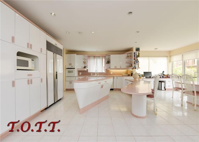 kitchen featuring sink, white appliances, white cabinets, and a kitchen island