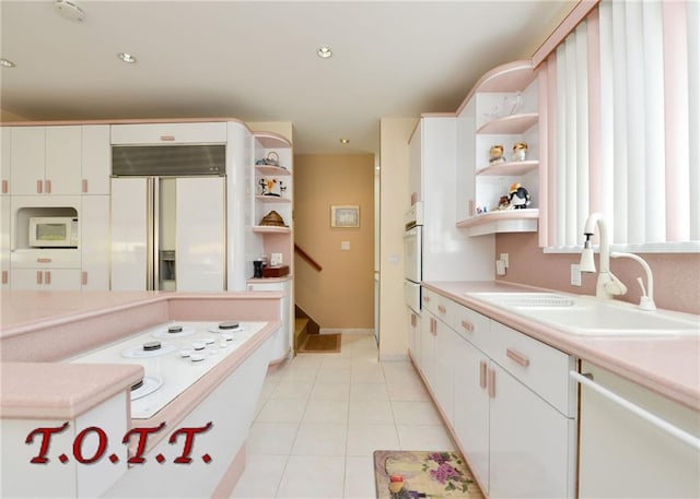 kitchen featuring white cabinets, light tile patterned floors, sink, and white appliances