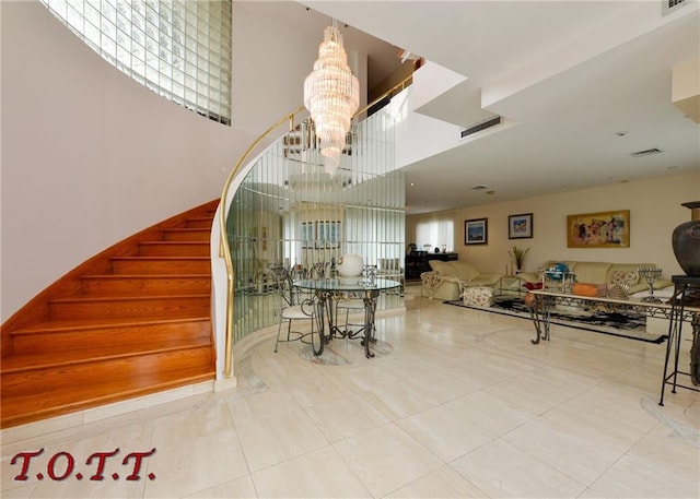 stairway with tile patterned flooring, a notable chandelier, and a high ceiling