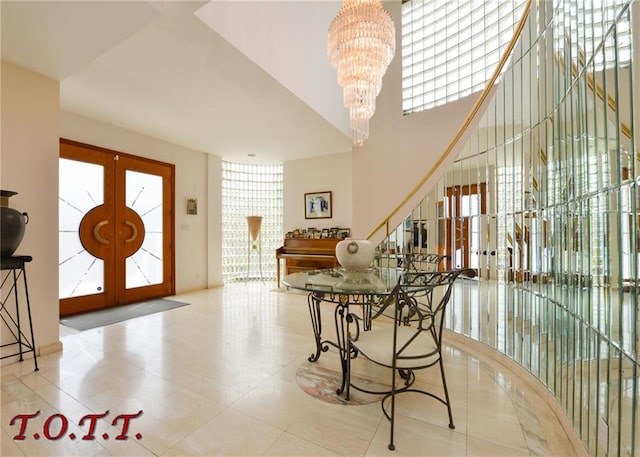 entrance foyer with light tile patterned floors, french doors, a notable chandelier, and a wealth of natural light