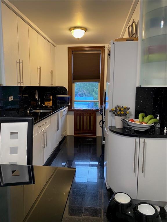 kitchen featuring white cabinetry, dishwasher, sink, and tasteful backsplash