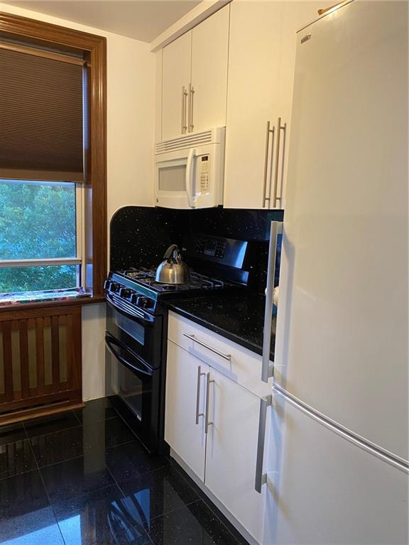 kitchen with white cabinetry and white appliances