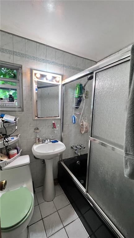 full bathroom featuring tile patterned flooring, tile walls, toilet, and combined bath / shower with glass door