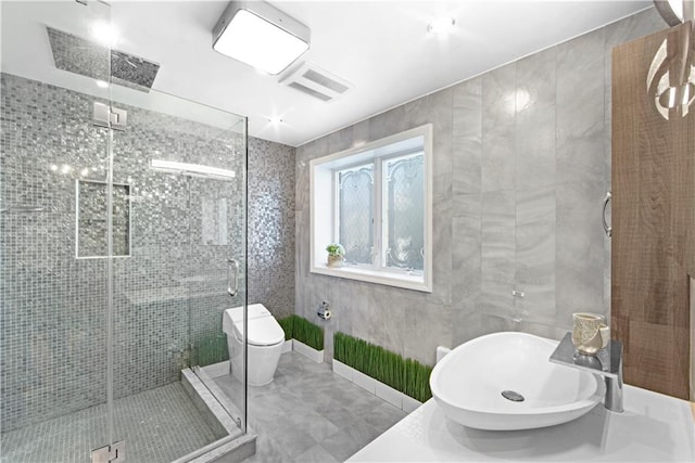 bathroom featuring walk in shower, toilet, sink, and tile walls