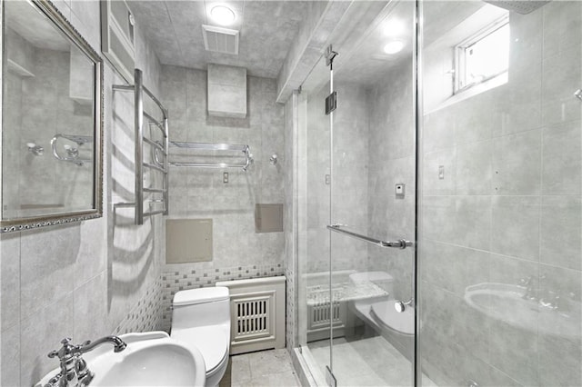 bathroom featuring tile patterned floors, toilet, a shower with shower door, sink, and tile walls