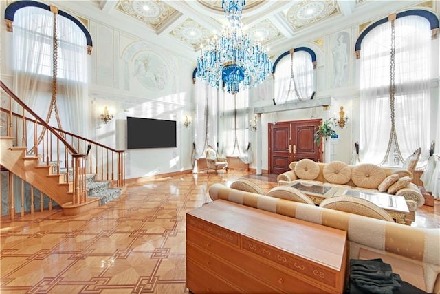 living room featuring coffered ceiling, a notable chandelier, a towering ceiling, and ornamental molding