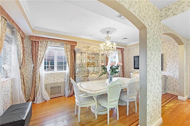 dining room featuring crown molding, wood-type flooring, radiator heating unit, and a healthy amount of sunlight