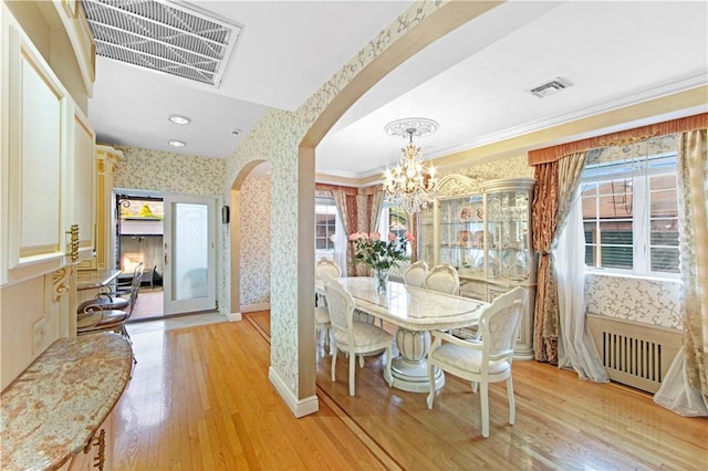 dining room featuring crown molding, radiator heating unit, a chandelier, and light hardwood / wood-style flooring