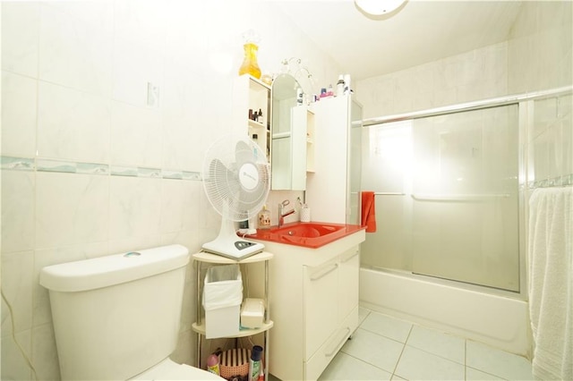 full bathroom with shower / bath combination with glass door, tile walls, toilet, tile flooring, and vanity