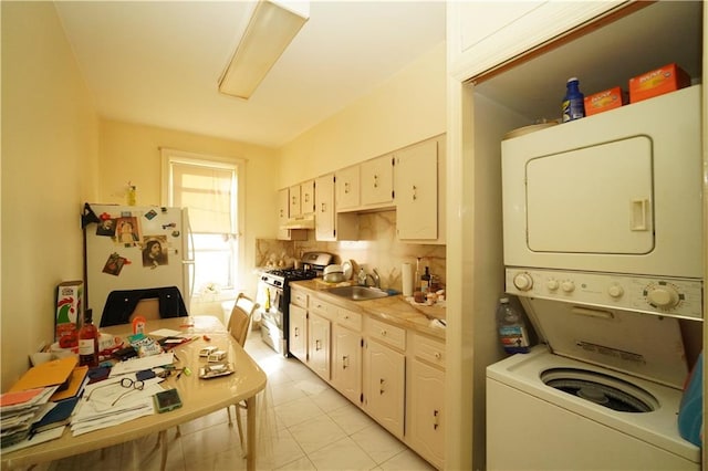 kitchen featuring stacked washer and dryer, white cabinets, sink, white appliances, and light tile floors