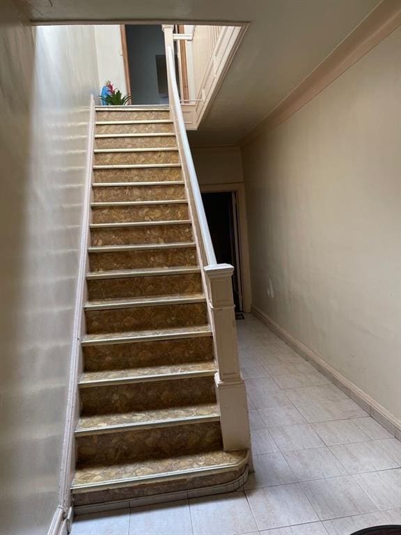 staircase with tile flooring and ornamental molding