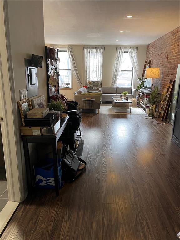 living room with brick wall and dark hardwood / wood-style floors