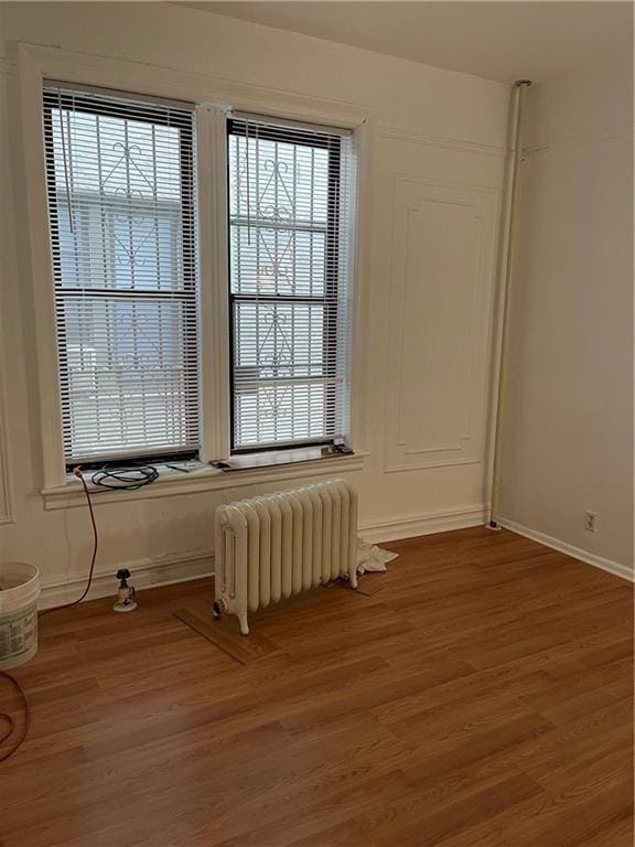 empty room featuring wood-type flooring and radiator