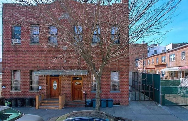 view of front of home with a gate, fence, and brick siding