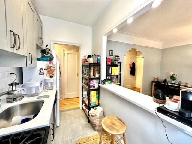 8020 4th Ave Unit D5, Brooklyn, NY 11209 - kitchen featuring light countertops, a sink, light wood-type flooring, backsplash, and range