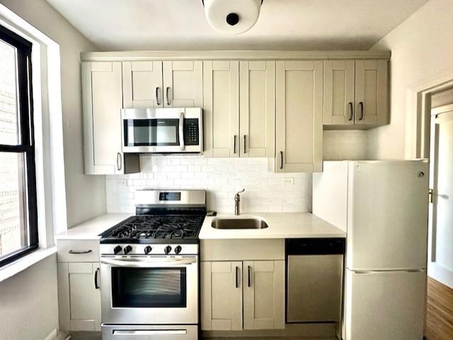 8020 4th Ave Unit D5, Brooklyn, NY 11209 - kitchen with appliances with stainless steel finishes, a sink, healthy amount of natural light, and light countertops