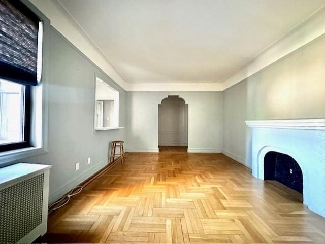8020 4th Ave Unit D5, Brooklyn, NY 11209 - unfurnished living room with arched walkways, radiator heating unit, baseboards, and a fireplace