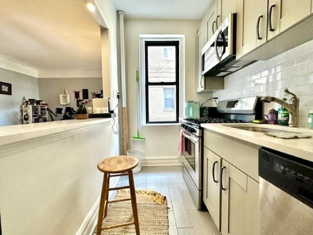 8020 4th Ave Unit D5, Brooklyn, NY 11209 - kitchen featuring appliances with stainless steel finishes, a sink, tasteful backsplash, light wood-type flooring, and light countertops