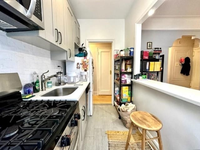 8020 4th Ave Unit D5, Brooklyn, NY 11209 - kitchen with appliances with stainless steel finishes, a sink, light countertops, decorative backsplash, and light wood-style floors