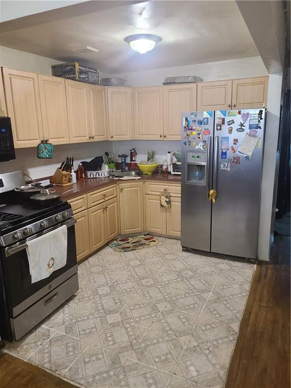 kitchen with light brown cabinetry, appliances with stainless steel finishes, and light hardwood / wood-style flooring