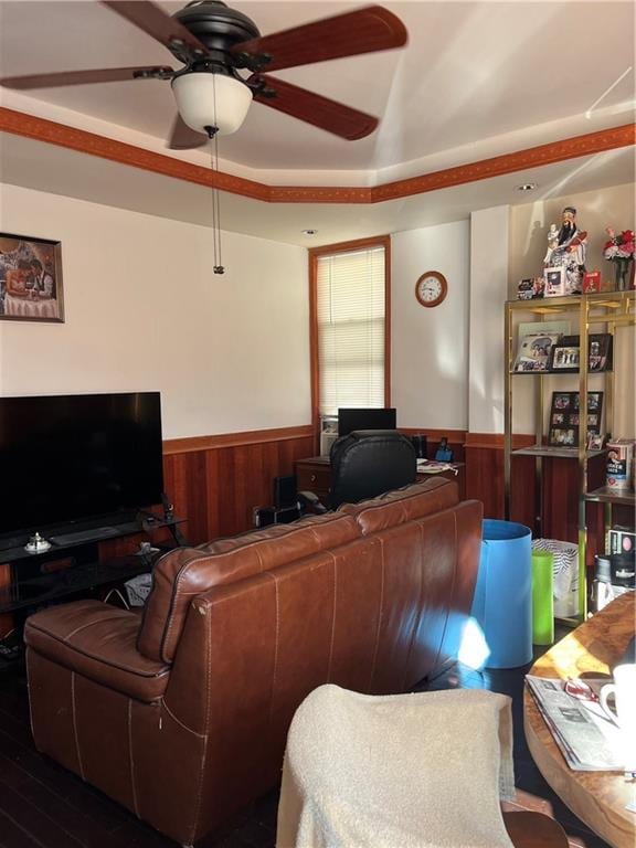 living room featuring a wainscoted wall, wood walls, and a ceiling fan