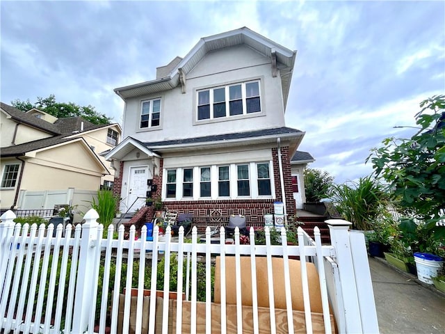 view of front of home featuring stucco siding, a fenced front yard, and brick siding