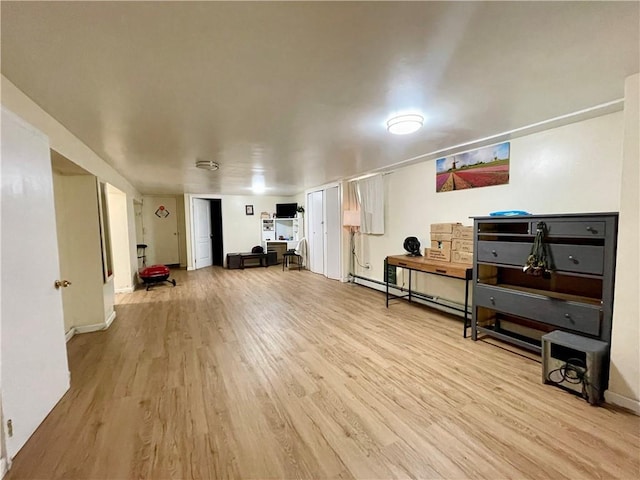 interior space featuring a baseboard radiator, light wood-style flooring, and baseboards