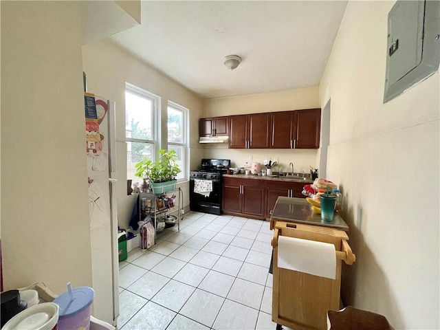 kitchen featuring black gas range, light tile patterned floors, electric panel, dark countertops, and a sink