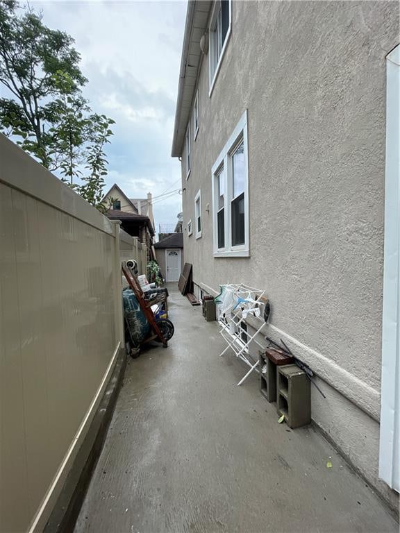 view of side of property featuring a patio area, fence, and stucco siding