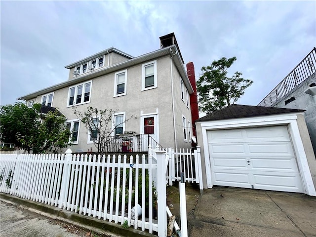 american foursquare style home with a fenced front yard, an outbuilding, stucco siding, a garage, and driveway