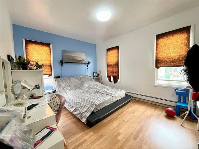 bedroom featuring light wood finished floors and baseboard heating