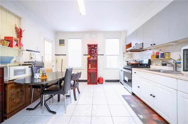 kitchen featuring gas range, white cabinetry, sink, decorative backsplash, and light tile patterned floors