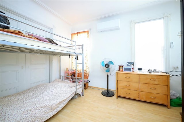 bedroom featuring light hardwood / wood-style floors, an AC wall unit, and ornamental molding