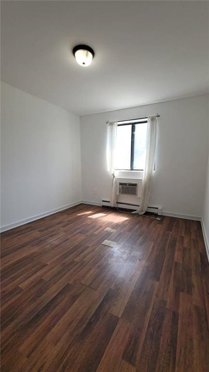 spare room with a baseboard heating unit, dark wood-type flooring, and a wall mounted AC