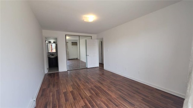 unfurnished bedroom featuring ensuite bath, dark hardwood / wood-style flooring, and sink