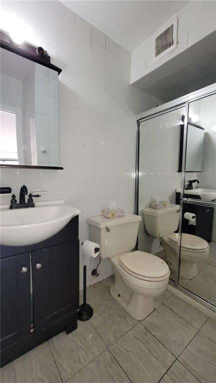 bathroom featuring tile patterned floors, vanity, toilet, and tile walls