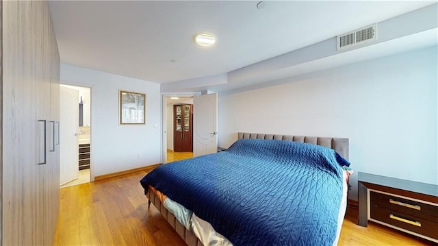 bedroom with light wood-type flooring and connected bathroom