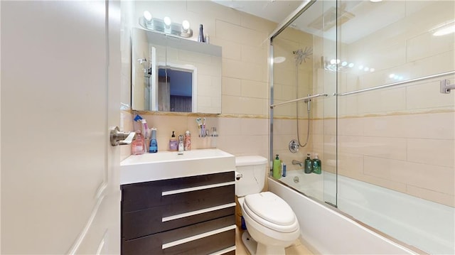 full bathroom featuring vanity, combined bath / shower with glass door, toilet, tile walls, and tasteful backsplash