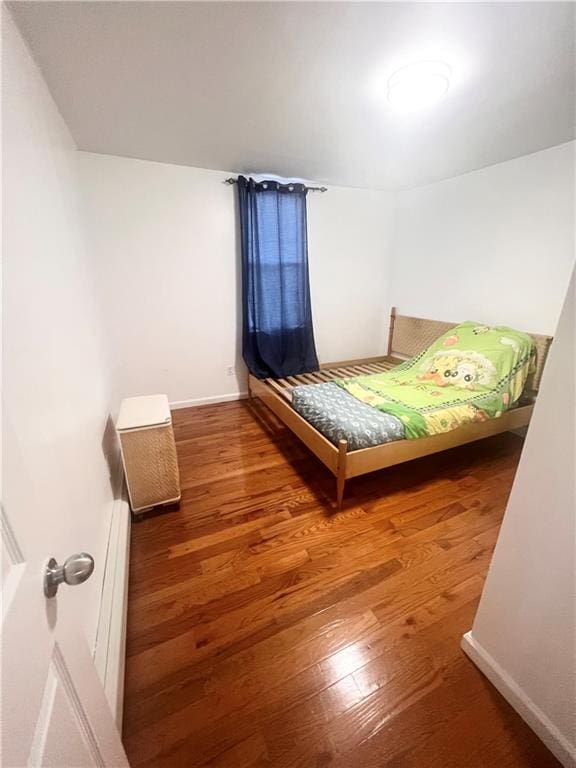 unfurnished bedroom with a baseboard radiator and hardwood / wood-style flooring