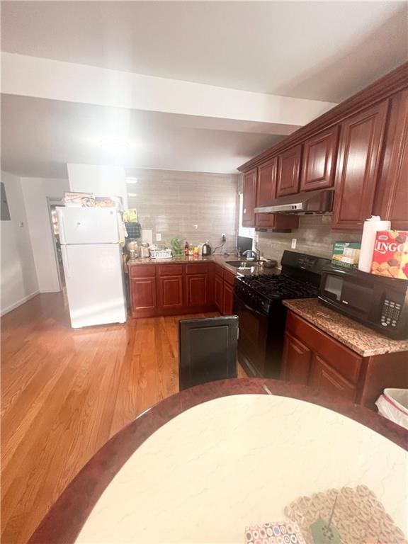 kitchen with tasteful backsplash, black appliances, and light hardwood / wood-style floors