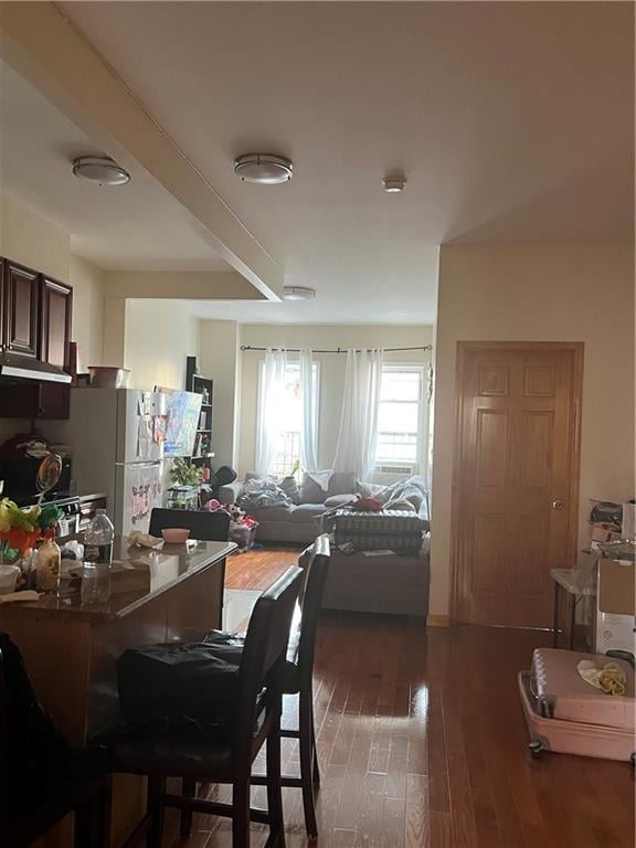 dining room featuring dark hardwood / wood-style flooring and beamed ceiling